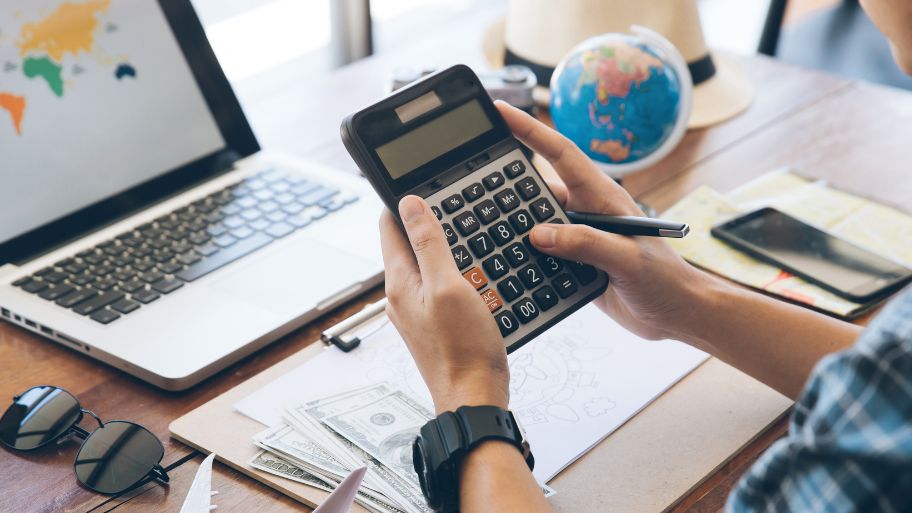 Adult Using Calculator in Budgeting Travel Expenses Adult Using Calculator in Budgeting Travel Expenses